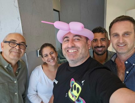 צוות "מיקוד משכנתאות" של רישרד הננפלד, כולל מספר עובדים מחייכים, מצטלמים יחד במשרד, כשאחד מהם חובש כובע מבלון.